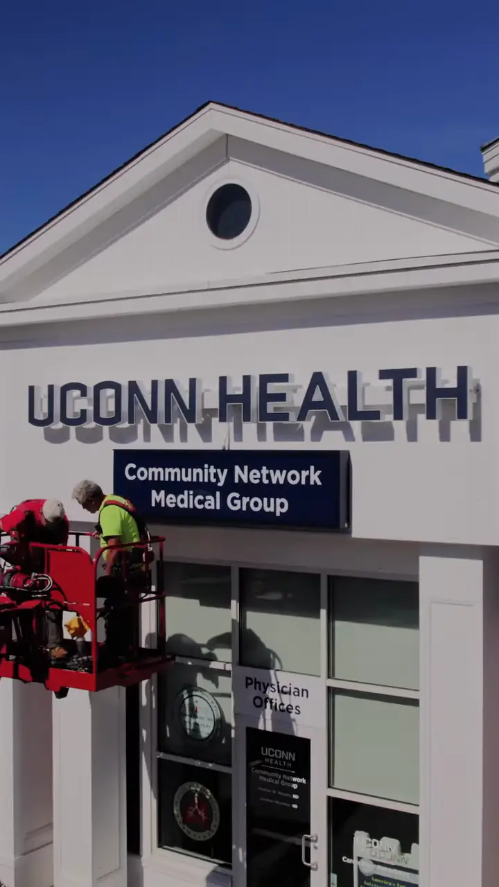 Sign Pro crews in lifts installing the UConn Health building sign